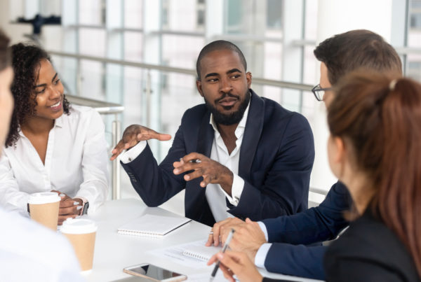 Black millennial boss leading corporate team during briefing in boardroom