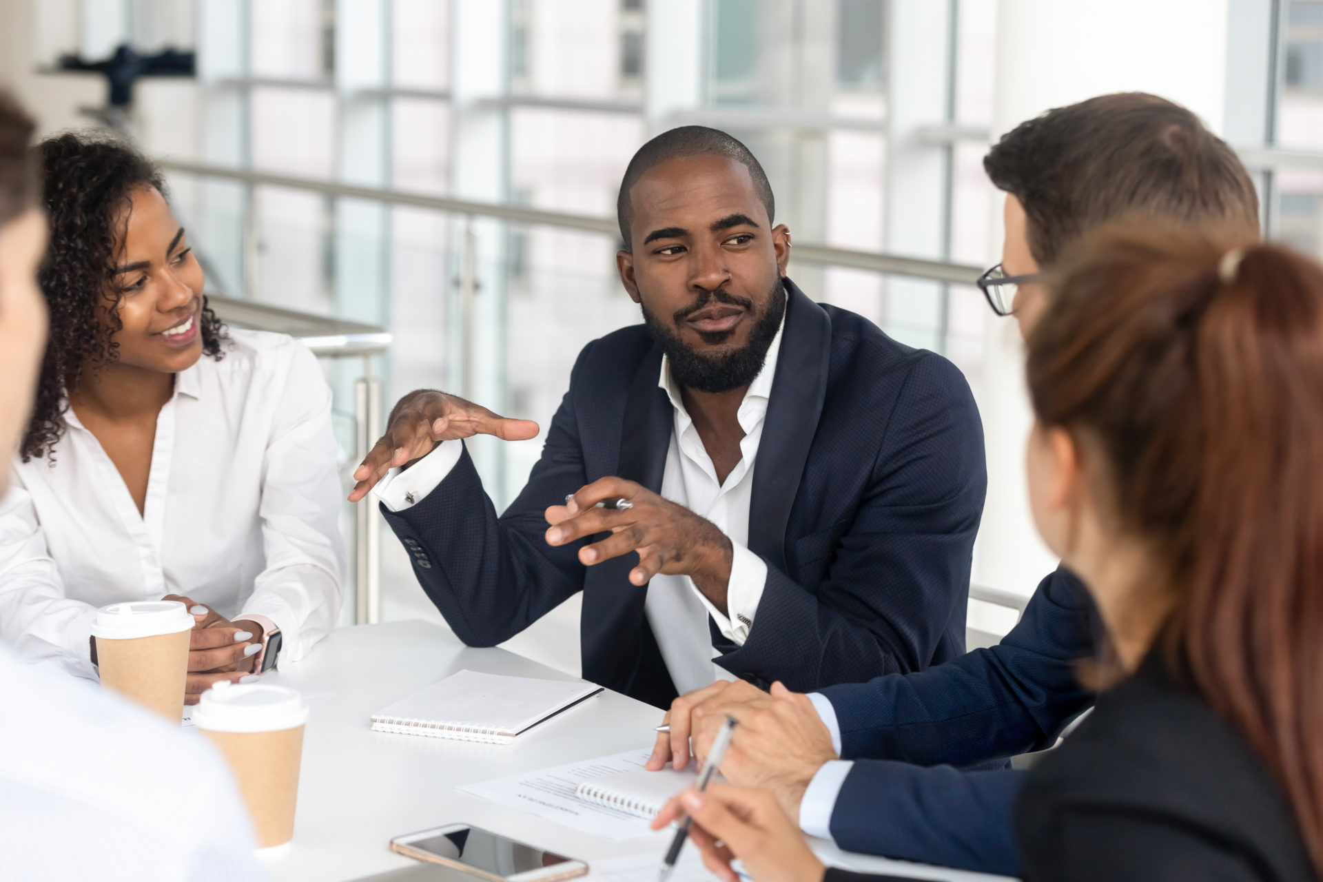 Black millennial boss leading corporate team during briefing in boardroom